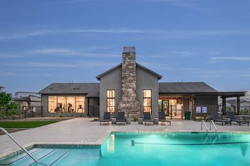 A modern house with a stone chimney and a pool in front.