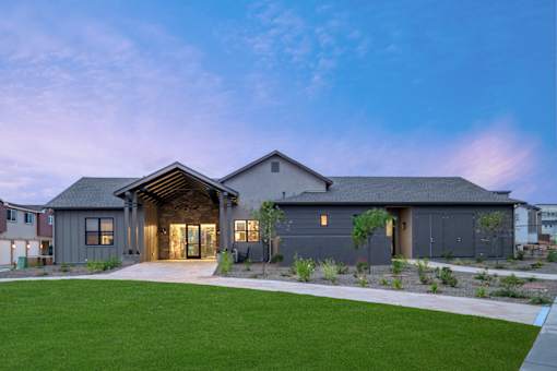 A modern house with a large front yard and a driveway.