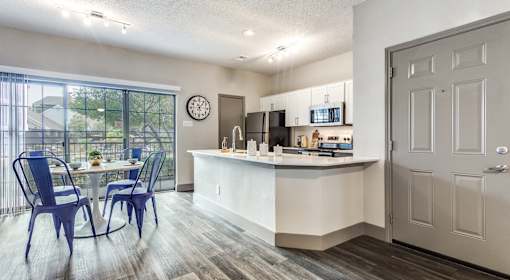 A kitchen with a dining table and chairs is shown.