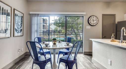 A dining room with a table set for two and a view of a balcony.