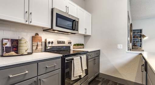 A kitchen with a black stove top oven and black cabinets.