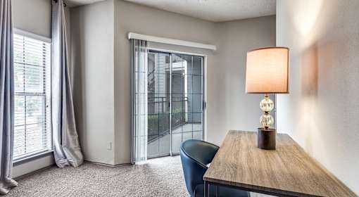 A room with a table, chair, and a lamp.