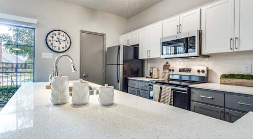 A kitchen with a white countertop and black appliances.