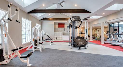 A spacious gym with a variety of equipment including treadmills, weights, and a rowing machine.