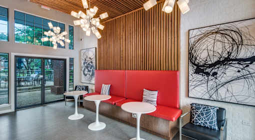 A modern cafe with a red booth and white tables.