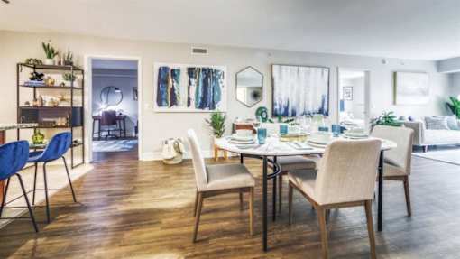 A dining room with a table set for four and a blue chair.