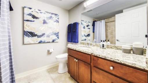 A bathroom with a toilet, sink, and a painting on the wall.