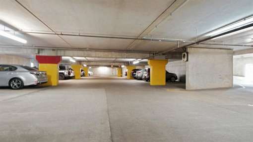 A parking garage with a few cars and yellow columns.