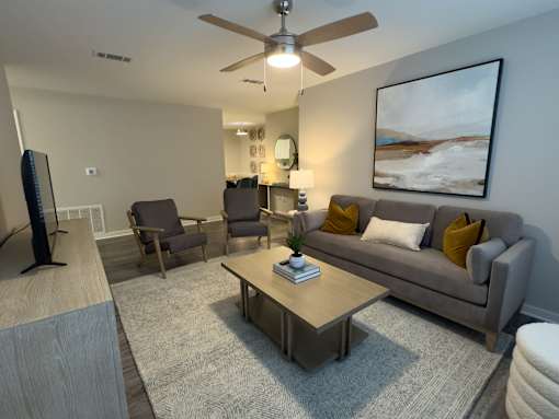 Twin Oaks Apartments in Hattiesburg Mississippi A living room with a grey couch, a coffee table, and a painting on the wall.