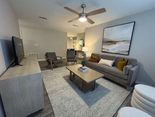 Twin Oaks Apartments in Hattiesburg Mississippi living room with a grey couch, a wooden coffee table, and a ceiling fan.