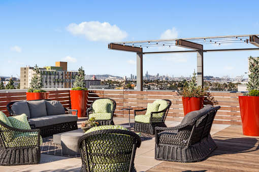 A patio with black wicker chairs and orange planters.