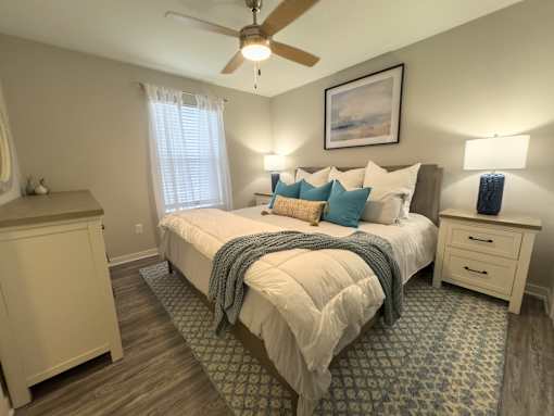 Twin Oaks Apartments in Hattiesburg Mississippi A bedroom with a bed, dresser, and ceiling fan.