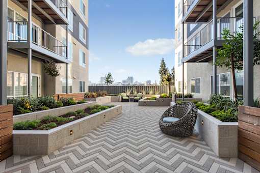 A modern courtyard with a woven chair and planters.