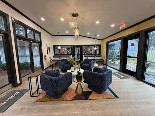 Spacious club room at Remington Place Apartments in Raleigh, NC with blue chairs and coffee table
