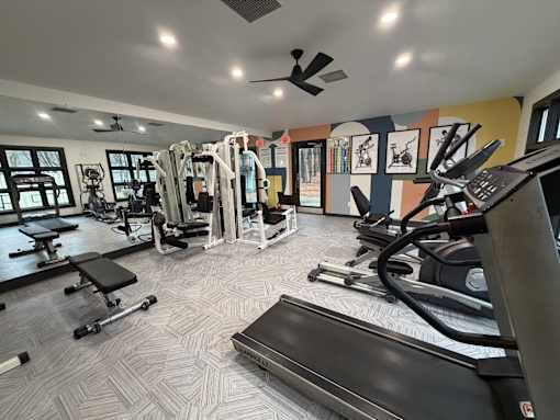 A gym with a variety of equipment including treadmills, weights, and exercise machines.