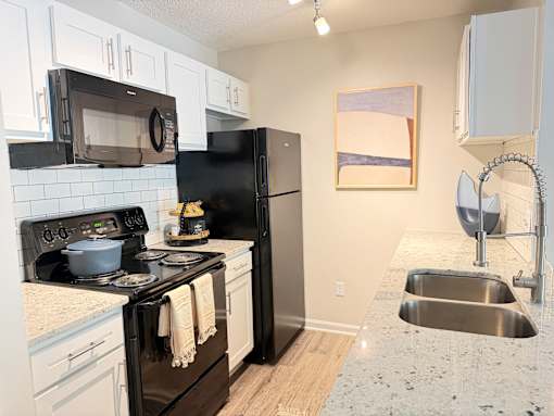 A kitchen with black appliances and white cabinets.