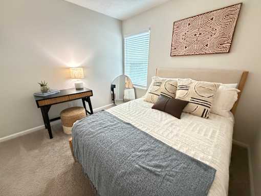 A bedroom with a bed, nightstand, and lamp.