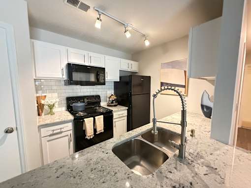 A kitchen with black appliances and granite countertops.