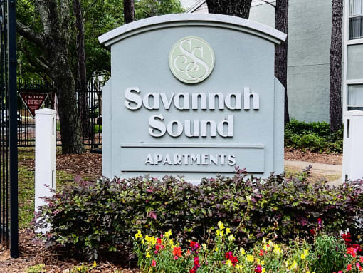a sign for savannah sound apartments in front of flowers