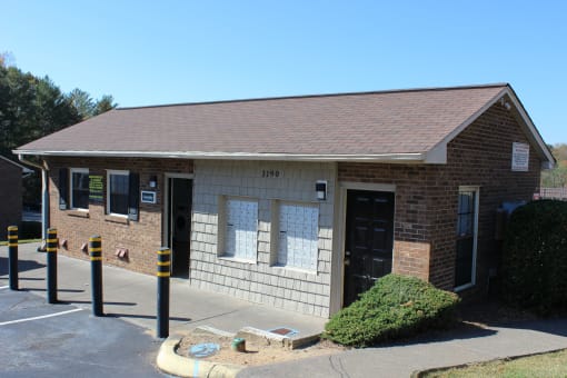 the front of a small brick building with a parking lot