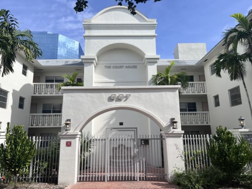 a white building with a gate and a palm tree