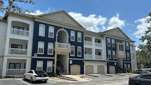 A white car is parked in front of a blue and white building.