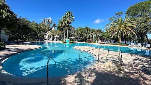 A large outdoor swimming pool surrounded by palm trees.