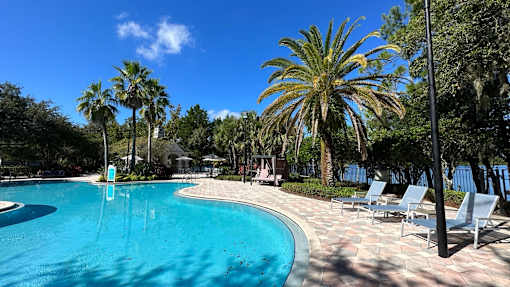 A swimming pool surrounded by palm trees and lounge chairs.