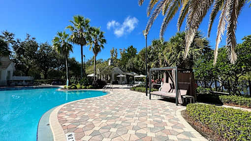 A pool area with a tiled walkway and palm trees.