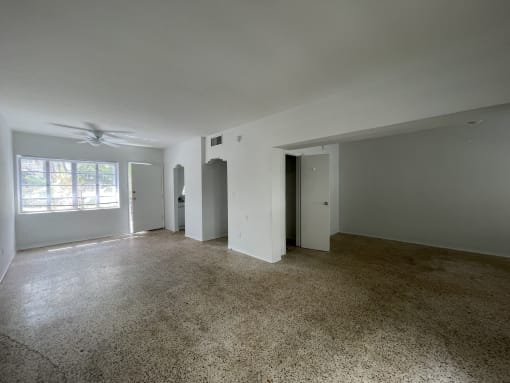 an empty living room with white walls and a ceiling fan