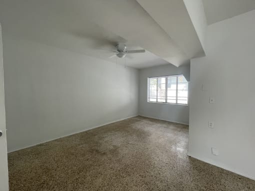an empty bedroom with a ceiling fan and a window