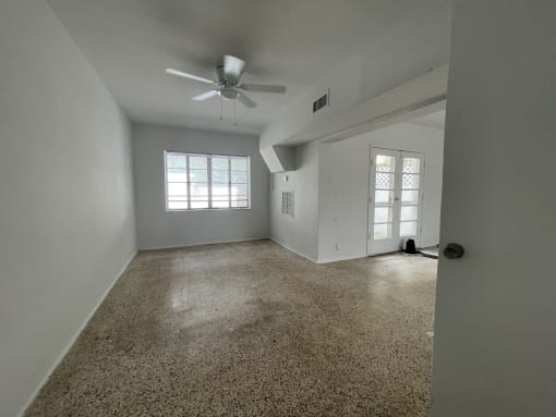 the living room of an empty house with a ceiling fan