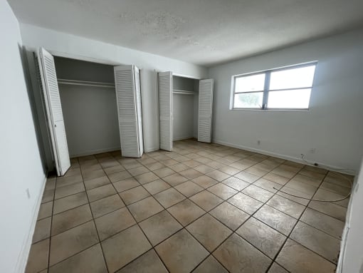 an empty living room with a window and two closets