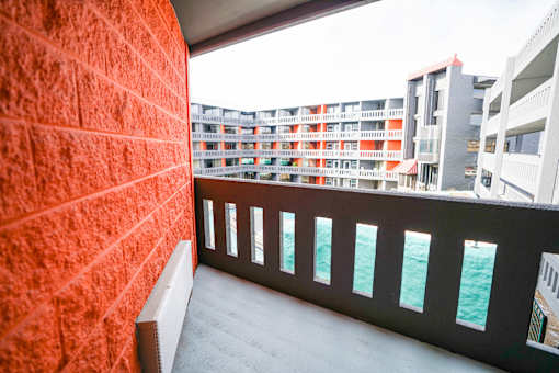 A balcony with a red wall and a view of the sea.