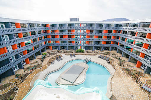 A large building with orange and grey balconies overlooks a pool.