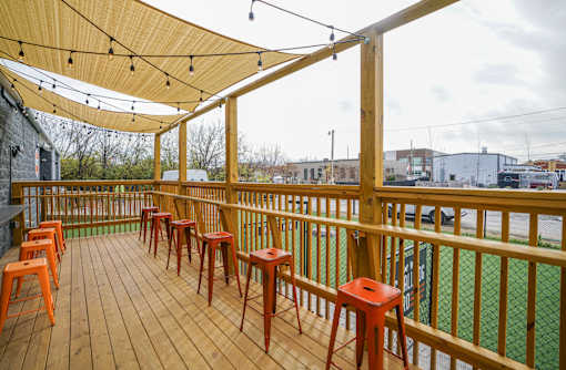 A wooden deck with orange stools and a yellow canopy.