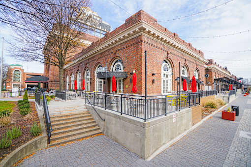 A red brick building with a black fence and stairs leading up to it.