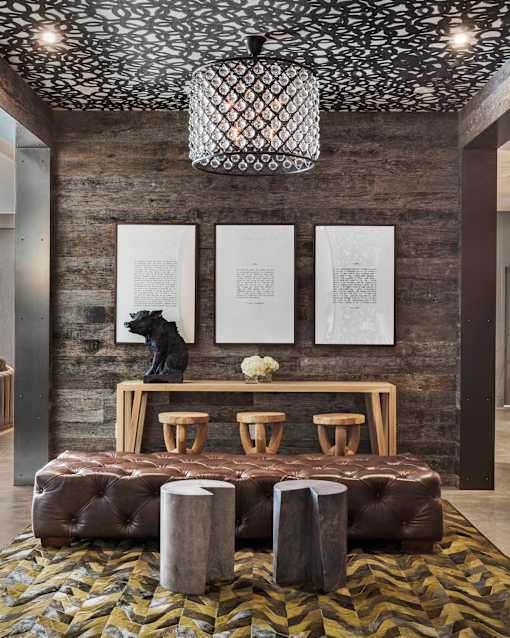 A room with a brown couch and a chandelier.