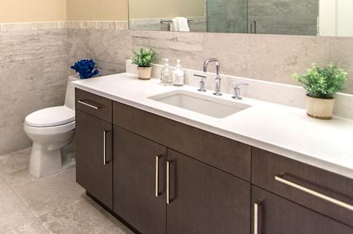 A bathroom with a toilet, sink, and brown cabinets.