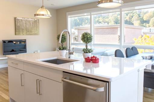 A modern kitchen with a white countertop and a stainless steel sink.