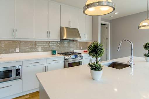 A kitchen with white cabinets and a white countertop.