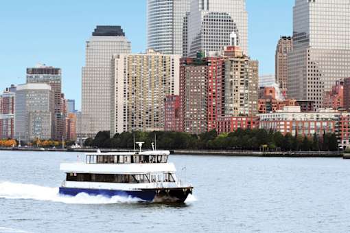 A boat is sailing on the water in front of a city skyline.