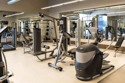 A gym with a variety of equipment including treadmills, weights, and exercise machines.