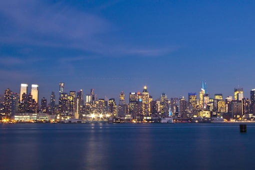 A city skyline at night with lights reflecting on the water.