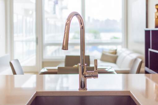 A kitchen sink with a copper faucet.