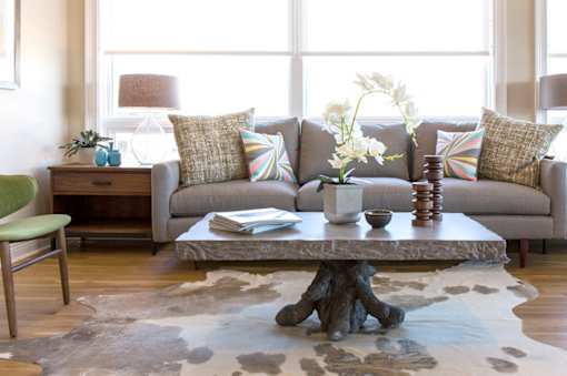 A living room with a grey couch, a green chair, and a cowhide rug.