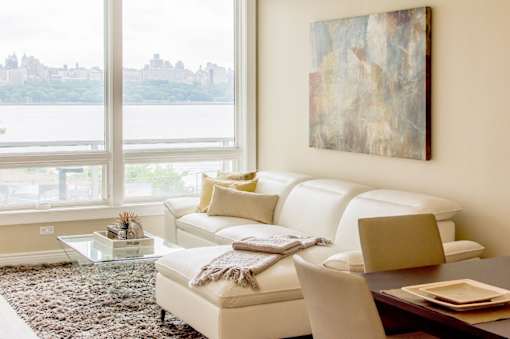 A living room with a white couch and a painting on the wall.