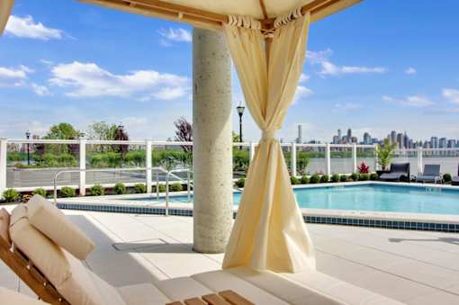 A poolside lounge chair with a yellow draped canopy.