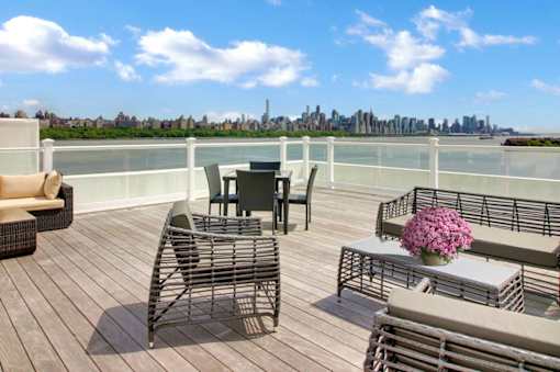 A balcony with a table and chairs overlooking a city skyline.