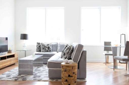 A modern living room with a grey sofa, a glass table, and a wooden coffee table.